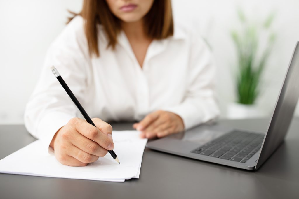 Unrecognizable Businesswoman Writing Business Report Near Laptop At Office, Cropped